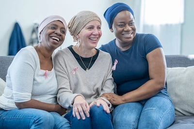 Three women sitting together on a couch, smiling
